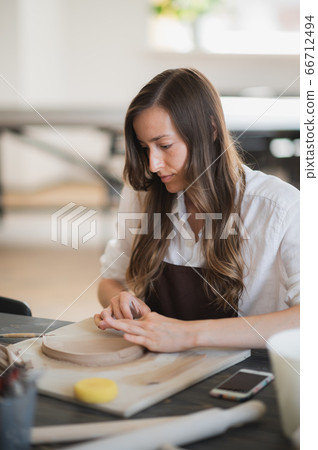 Woman's fingers adding and adjusting a clay part on a future ceramic product. Woman's fingers adding and adjusting a clay part on a future ceramic product. 66712494