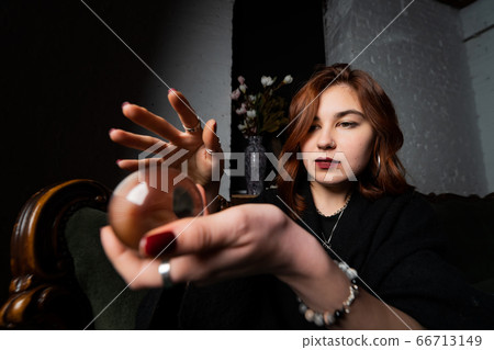 Woman in black suit holding crystal ball 66713149