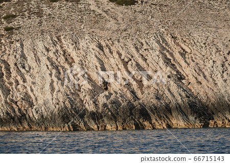 Beautiful high cliff with caves and hanging rocks of a mountain in Adriatic sea, a crevice, colorful Beautiful high cliff with caves and hanging rocks of a mountain in Adriatic sea, a crevice, colorful 66715143