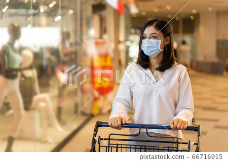 young woman with shopping cart in department store 66716915