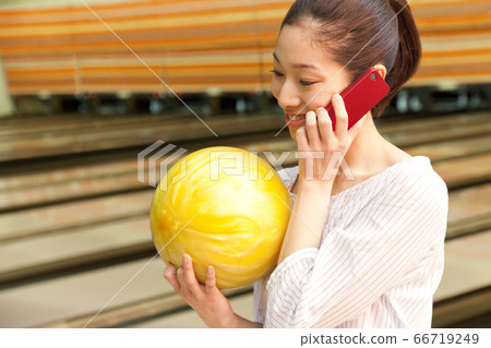 Woman making a phone call at bowling alley Woman making a phone call at bowling alley 66719249