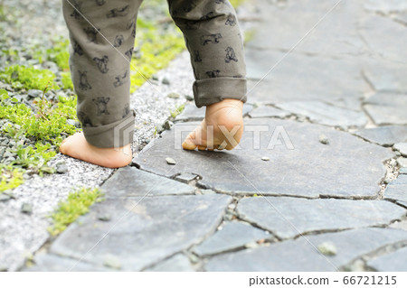 Both feet of a child walking barefoot on a cobblestone 66721215