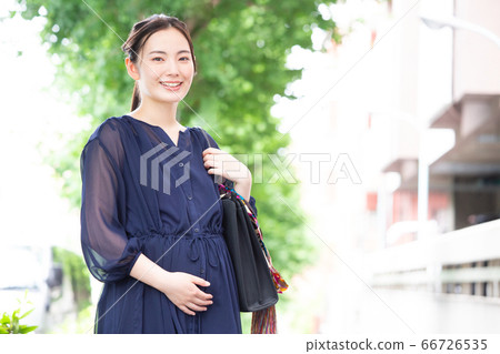 禮服的一名工作的孕婦對照相機的微笑 禮服的一名工作的孕婦對照相機的微笑 66726535