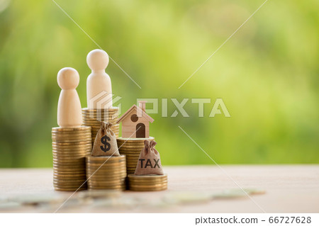 Couple and home model on rows of rising coins, US dollar bags on a table. Concept house or building or land value, property tax, local development tax depicts ad valorem tax on value of a property 66727628