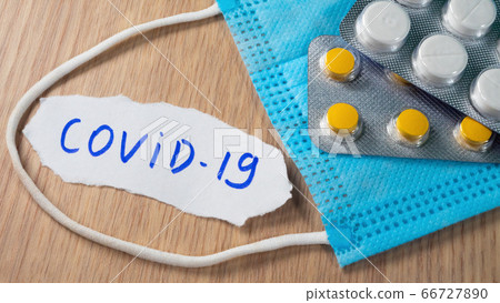 Novel coronavirus COVID-19 text on paper near blue medical face mask 66727890