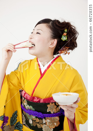 Woman in furisode eating mochi 66728355