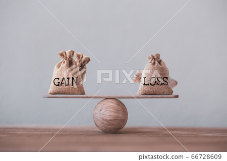 Gain and loss bags on a basic balance scale on blackboard. Capital investment gain and loss, financial concept, depicts balancing between profit and loss while managing assets e.g bonds, stocks, deriv 66728609