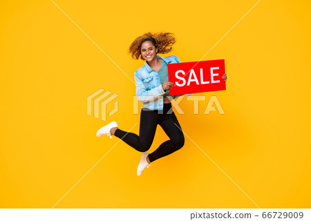 Surprised smiling woman jumping with red sale sign 66729009