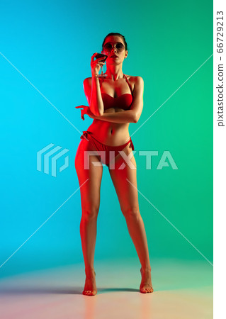 Fashion portrait of seductive girl in stylish swimwear posing on a bright gradient background. Summertime, beach season 66729213