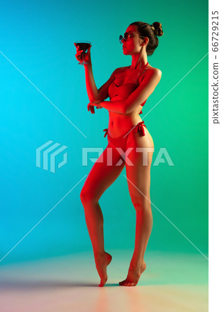 Fashion portrait of seductive girl in stylish swimwear posing on a bright gradient background. Summertime, beach season 66729215