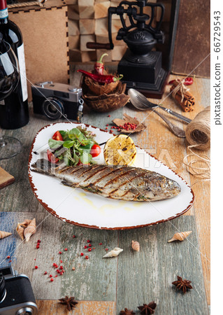 Grilled trout fish with salad and lemon Grilled trout fish with salad and lemon 66729543