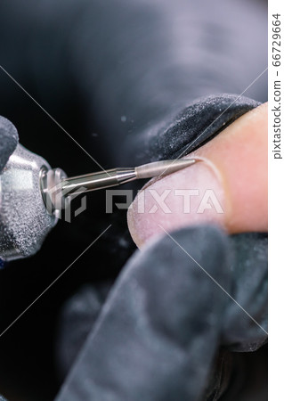 Process manicure close-up. Preparation for hardware manicure. Beautician in rubber gloves cuts the cuticle and processes nails. Process manicure close-up. Preparation for hardware manicure. Beautician in rubber gloves cuts the cuticle and processes nails. 66729664