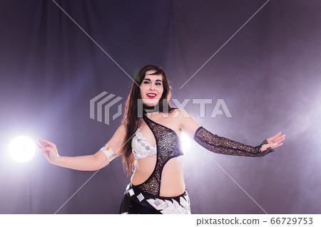 Young woman belly dancer in exotic dress with gold, dancing tribal fusion dance in studio. 66729753