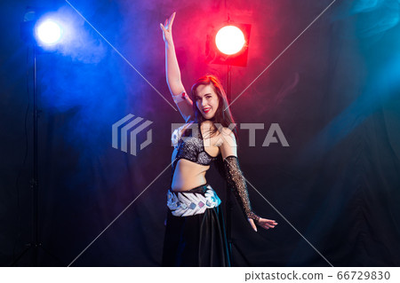 Young woman belly dancer in exotic dress with gold, dancing tribal fusion dance in studio. Young woman belly dancer in exotic dress with gold, dancing tribal fusion dance in studio. 66729830