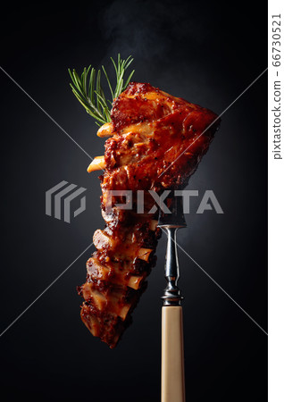 Grilled pork ribs with rosemary on a fork. Grilled pork ribs with rosemary on a fork. 66730521