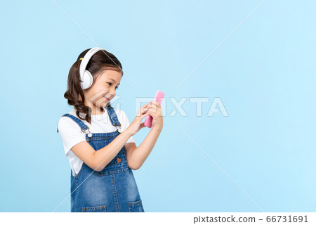 Cute 8 year-old girl wearing headphones listening to music online Cute 8 year-old girl wearing headphones listening to music online 66731691