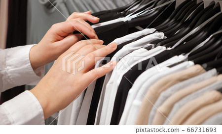 Female hands sorting cotton pullovers on a hanger in a clothing store Female hands sorting cotton pullovers on a hanger in a clothing store 66731693