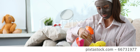Girl with cosmetic mask on her face does cleaning Girl with cosmetic mask on her face does cleaning 66731977