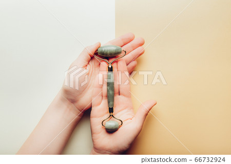 Jade face roller in hands 66732924
