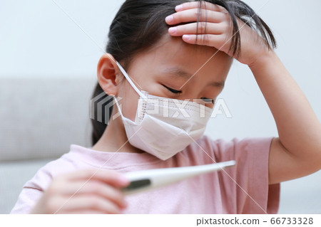 An infant who is in poor physical condition wearing a mask to measure body temperature 66733328