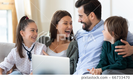 Laughing mother and father with children using laptop at home 66733470