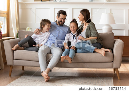 Happy parents with son and daughter relaxing on couch Happy parents with son and daughter relaxing on couch 66733514