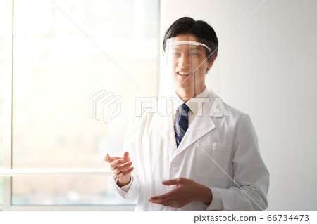 A man in a white coat with a face shield A man in a white coat with a face shield 66734473