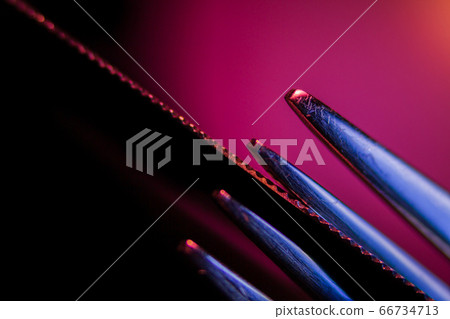 Edge of an illuminated  serrated knife and prongs 66734713