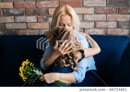 Mom kisses and hugs her little daughter, who gave her a bouquet of flowers Mom kisses and hugs her little daughter, who gave her a bouquet of flowers 66734861