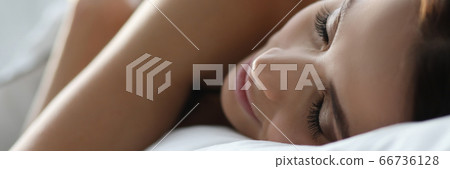 Young woman sleeping peacefully on white bedding Young woman sleeping peacefully on white bedding 66736128
