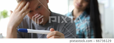 Man rubs his forehead looking at pregnancy test Man rubs his forehead looking at pregnancy test 66736129