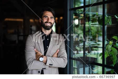 Portrait of businessman with jacket standing indoors in restaurant. 66736997