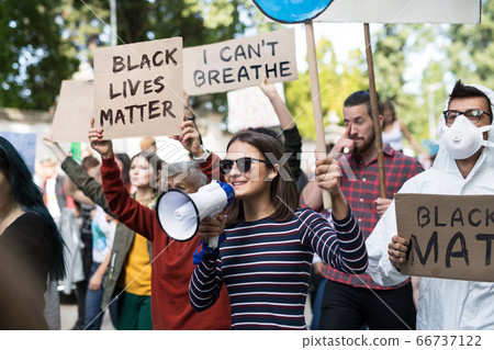 Black lives matters protesters with megaphone holding signs and marching outdoors in streets. 66737122