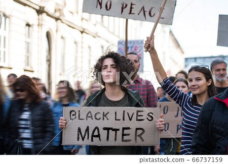 Black lives matters protesters holding signs and marching outdoors in streets. 66737159