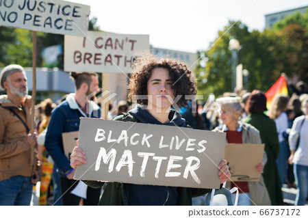 Black lives matters protesters holding signs and marching outdoors in streets. 66737172