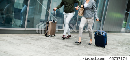 Midsection of businesspeople with luggage going on business trip, running at the airport. 66737174