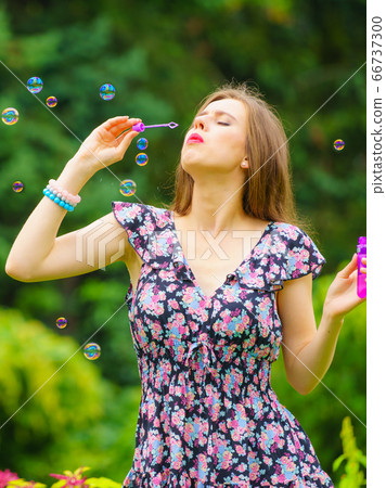 Woman blowing soap bubbles, having fun Woman blowing soap bubbles, having fun 66737300