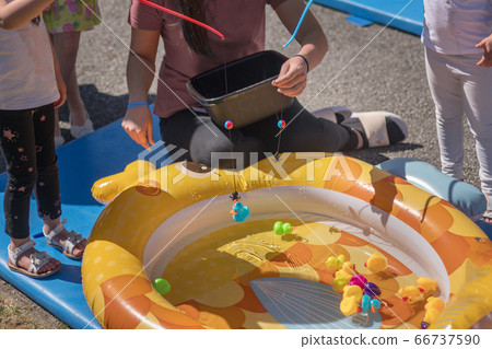 Girls catch rubber ducks with fishing rod 66737590