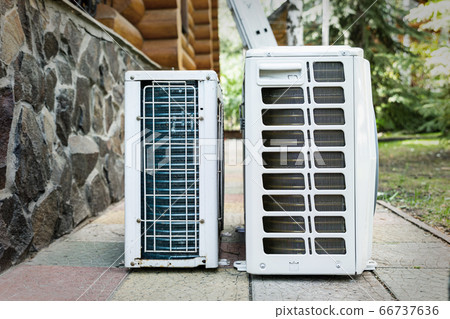 New modern HVAC air conditioning external compressor unit preapred for installation or replacement near wall of wooden log residential country cottage. Ladder and equipment for service and maintenance 66737636