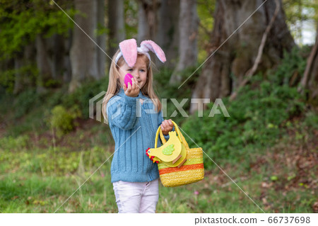 Girl with bunny ears collects the eggs for Easter Girl with bunny ears collects the eggs for Easter 66737698