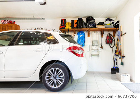 Home suburban car garage interior with wooden shelf , tools and equipment stuff storage warehouse on white wall indoors. Vehicle parked at house parking background 66737706