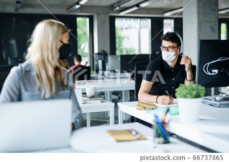 Young people with face masks back at work or school in office after lockdown. 66737865