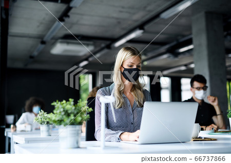 Young people with face masks back at work or school in office after lockdown. Young people with face masks back at work or school in office after lockdown. 66737866