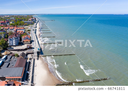 Top view of the Baltic sea coast. You can see the resort town of Zelenogradsk, the promenade, breakwaters, the blue sea and a sandy strip of beach stretching into the distance. 66741811
