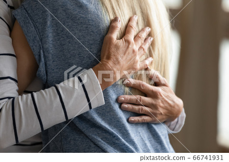 Close up cropped image elderly mother hugs grownup daughter Close up cropped image elderly mother hugs grownup daughter 66741931