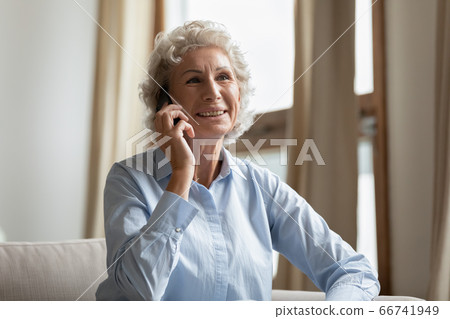 Middle-aged woman enjoy pleasant conversation with relatives using smartphone Middle-aged woman enjoy pleasant conversation with relatives using smartphone 66741949