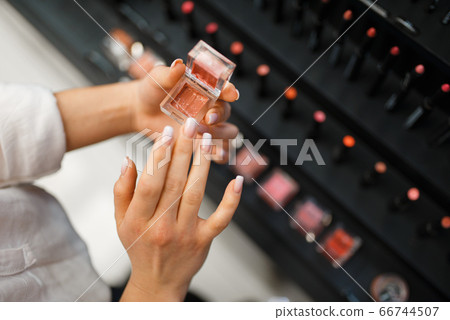 Woman holds lipstick tester in cosmetics store Woman holds lipstick tester in cosmetics store 66744507