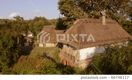 Close-up few small houses with thatched roof and white walls in the forest. Close-up few small houses with thatched roof and white walls in the forest. 66746117