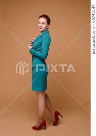 Smiling fashionable woman with red hair in green Smiling fashionable woman with red hair in green 66746144