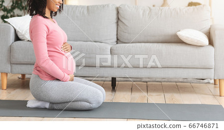 Cropped profile photo of pregnant woman exercising at home Cropped profile photo of pregnant woman exercising at home 66746871